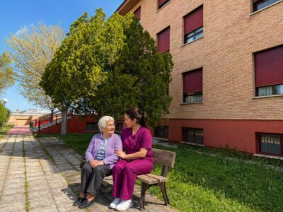 Gerocultora acompañando a una residente en el jardín de una residencia de mayores Gerocultora acompañando a una residente en el jardín de una residencia de mayores